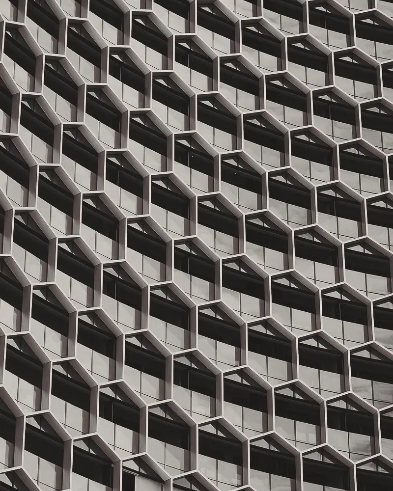 Repeating modules of a white concrete facade, seen from below.