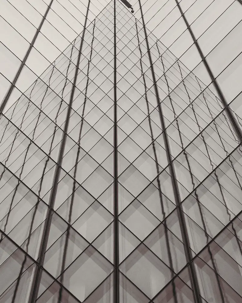 Looking up at a diamond-gridded glass tower.